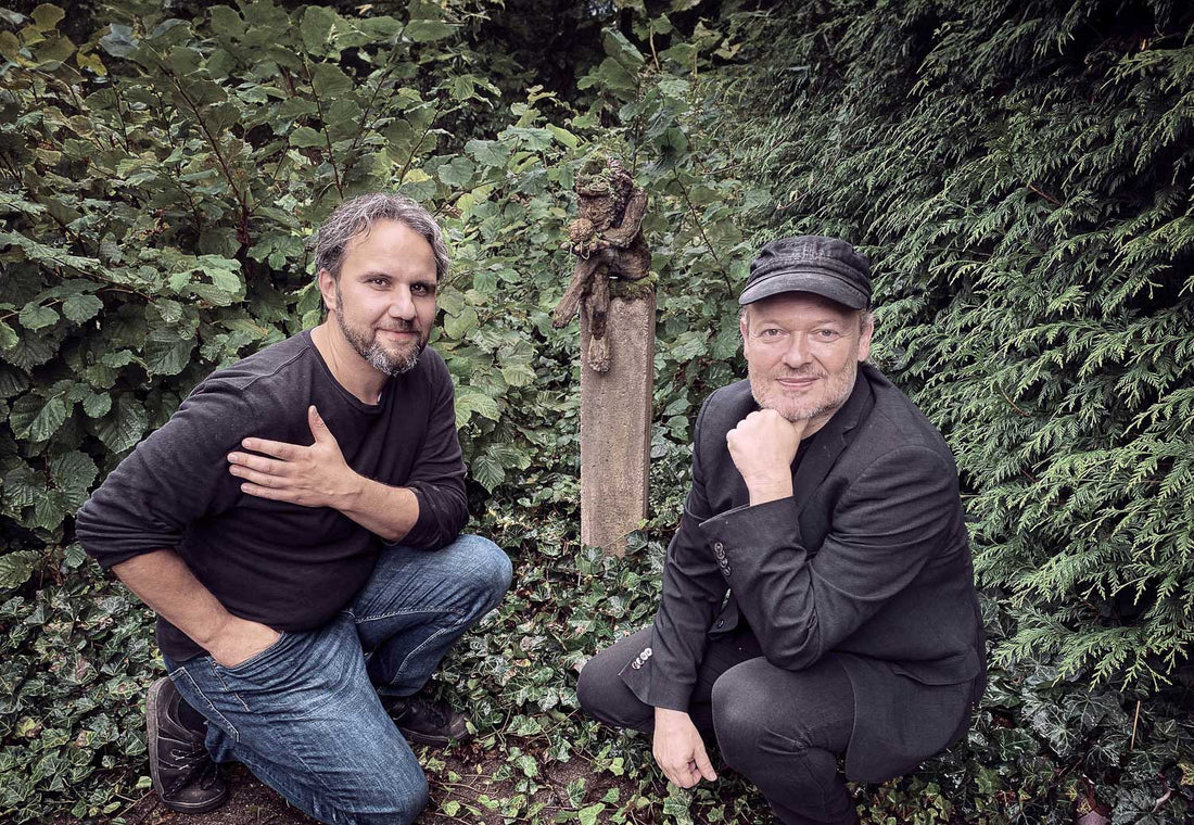 roland straller und michael schmidt-salomon knieend vor affe mit hirn skulptur