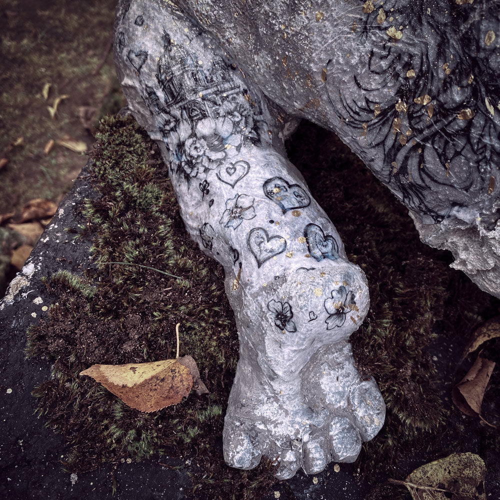 detailansicht von seinem linken beinchen, ebenfalls übersät vont herzchen -und blüten-tattoos