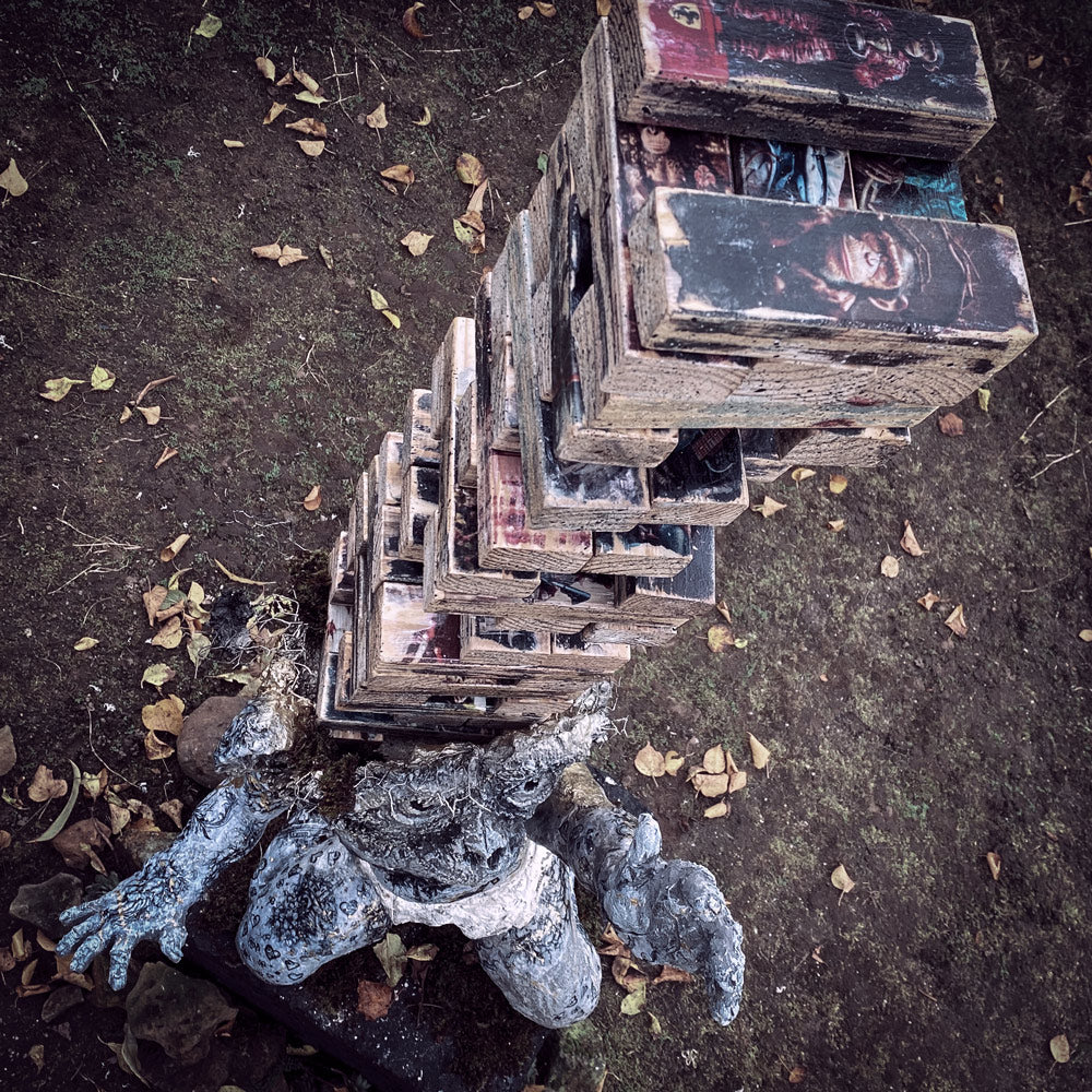 ansicht von oben auf baby champ skulptur mit einem riesen jenga wackelturm aus bauklötzen, der aus seinem kopf ragt - jeder klotz mit einem schimpansenbild beklebt