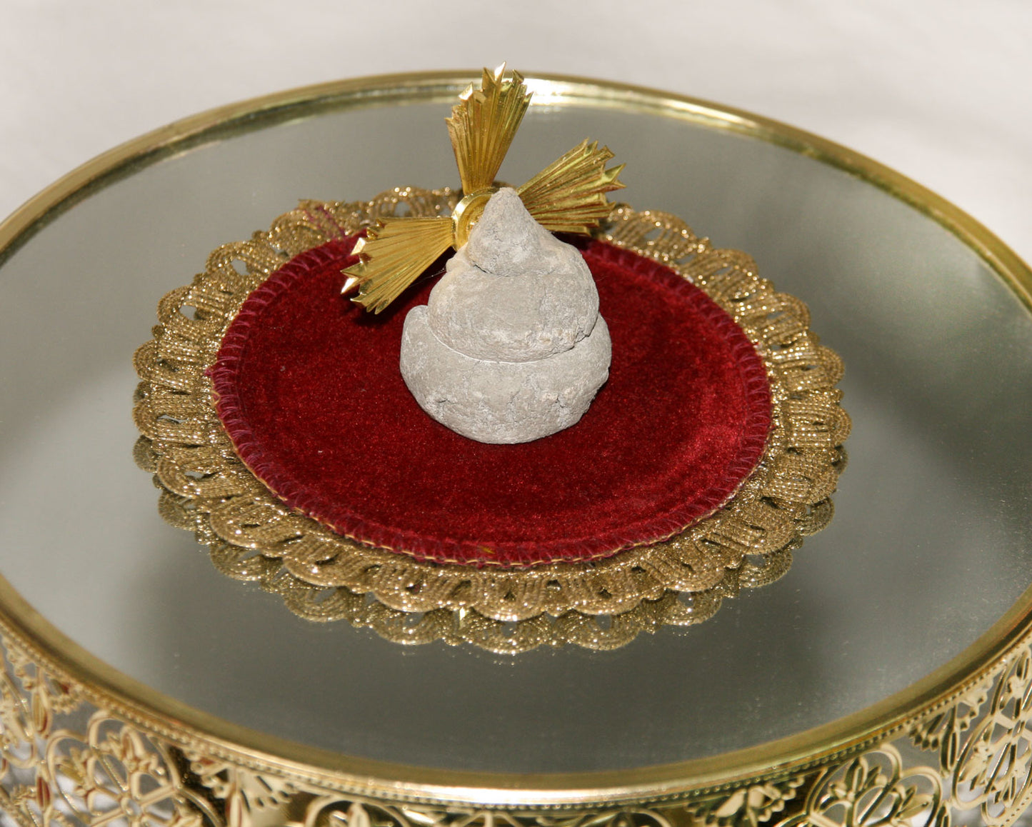 nahaufname von versteinerte Kackhaufen, der angbelich vom kleinen jesus sein soll, verziert mit einer goldenen gloriole auf eine brokat deckchen