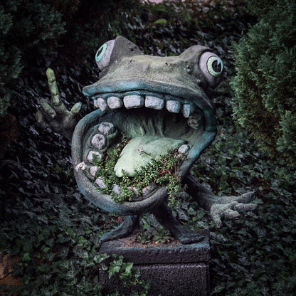 aus seinem riesigen frosch maul erspriessen pflanzen, er zeigt und klagt an umrankt von efeu im garten von roland straller