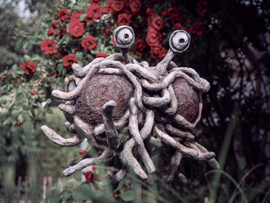 das FSM mit seinen nudeligen Anhängsel schwebend vor Rosenstrauch - von vorne
