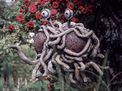 das FSM mit seinen nudeligen Anhängsel schwebend vor Rosenstrauch -halbprofil - ein nudel streckt er aus zum touchen